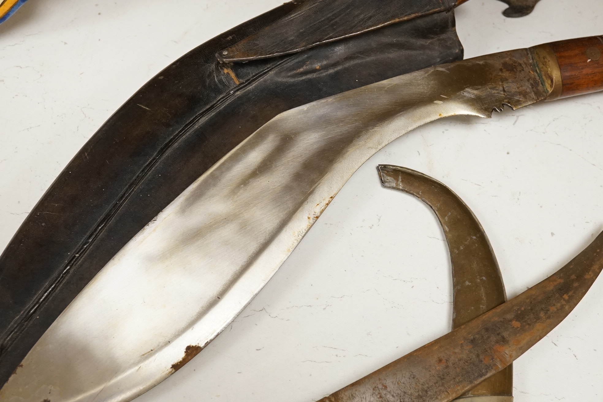 An Indian Kukri with brass mounted wooden handle its leather sheath, and a Moroccan Jambiya, together with a hardstone and wrought iron candle stand